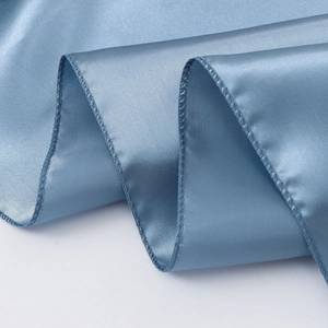Close-up of blue satin table runner showing smooth silk texture and fine stitched edges
