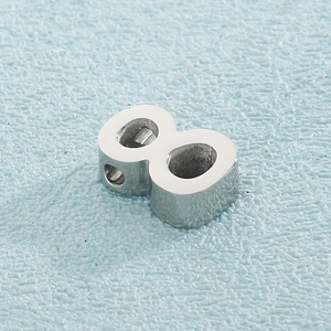 Macro shot of silver metal number 8 charm with polished finish and side perforation