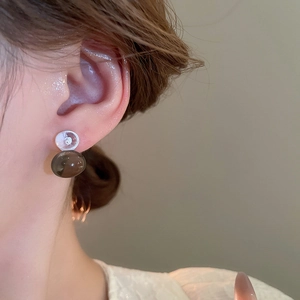 Close-up of semi-transparent brown round bead stud earring worn by a model