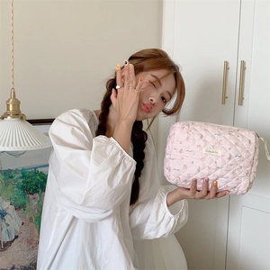 Modèle tenant une trousse à maquillage matelassée rose avec motifs d'ours et fermeture