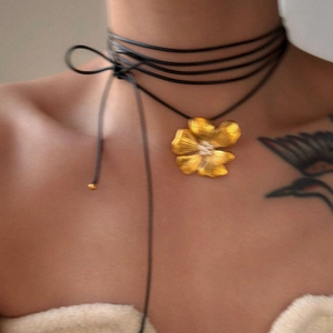 Detail of 18k gold floral pendant with multi-layer black cord and bow tie choker