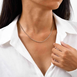 Detail view of a 3mm silver beaded stainless steel chain worn on a model neckline