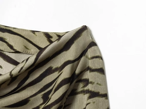 Detailaufnahme von grün-braunem Zebradruck auf seidigem Satingewebe mit feinen Nähten