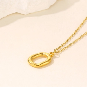 Minimalist gold irregular oval pendant necklace on a clean white stone and beige surface