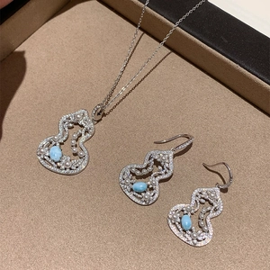 Silver jewelry set with gourd pendants, blue gemstones and pearls on brown velvet lining