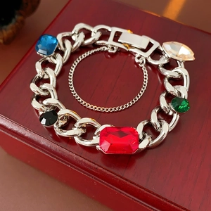 Detail of silver link bracelet with large colorful gems on a vintage wooden box