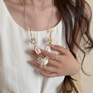 Detail of starfish and shell pendant necklace with pearl bow on wax cord chain