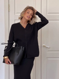 Close-up of black knitted V-neck cardigan and matching skirt with leather handbag