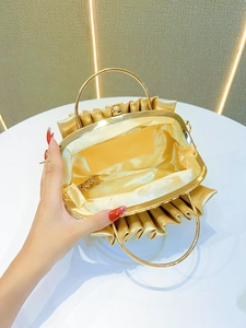 Gold pleated evening clutch with metal ring handle and chain strap showing inner structure