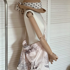 Detail of light pink linen tote bag with black leaf prints on a wooden mannequin