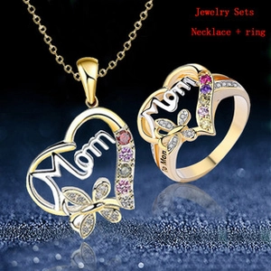 Detail of Mom heart necklace and ring set with rhinestones and butterfly on blue background