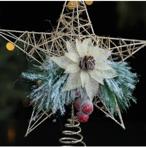Close-up of golden iron Christmas tree star topper with pine needles and red berries