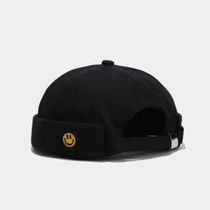 Detailed view of the embroidered yellow smiley face on the black cotton docker hat