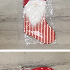 Detail of red and white striped Christmas stocking with a plush gnome decoration