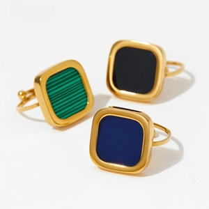 Detail view of square gold rings with malachite green, black and blue stone inlays