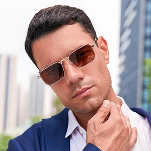 Close-up of premium gold metal frame sunglasses with brown lenses on male model in a suit