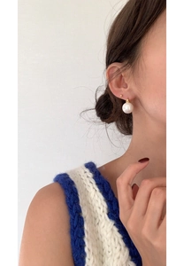Close-up of model wearing elegant pearl earrings with gold clasp on white background
