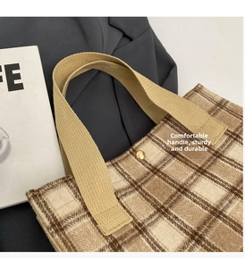 Detail of tweed checkered tote bag showing woven handles and gold magnetic closure