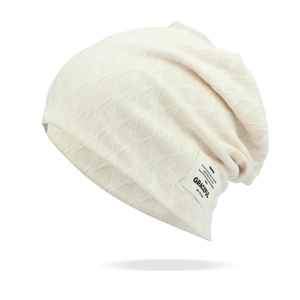 Close-up of beige slouchy beanie with textured diamond knit pattern and side fabric label