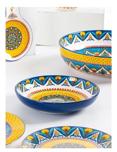 Detail of bohemian style ceramic tableware with vibrant hand-painted patterns on white background
