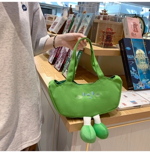 Detail of cute green canvas tote bag featuring 3D plush feet and unique facial embroidery