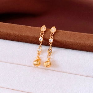 Macro shot of 24k gold-plated round pumpkin pendant earrings with sparkling zircons