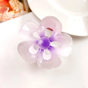 Close-up of a translucent purple frangipani flower hair claw clip with metal spring