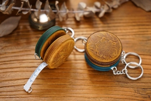 Detail of vintage floral embossed leather mini tape measures with metal keychains