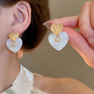 Dettaglio ravvicinato di orecchini a cuore placcati oro 24k con madreperla e zirconi