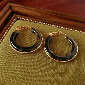 Detailed shot of retro gold plated resin hoop earrings on green fabric background