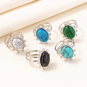 Collection of five vintage stainless steel rings with colorful oval stones on beige cloth