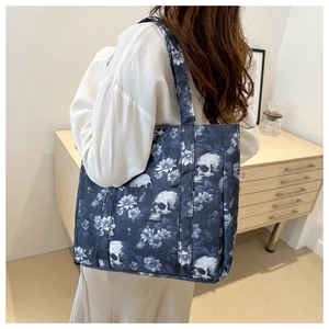 Detail shot of navy tote bag featuring white floral skull print and durable shoulder strap