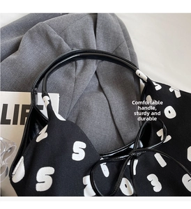 Detail of printed canvas bucket bag with black glossy handles on grey suit fabric