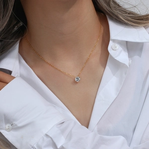 Gros plan d'un collier doré avec un pendentif solitaire en zircon blanc porté par un mannequin