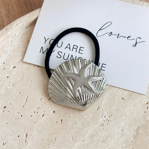 Detail shot of silver seashell hair tie with starfish pattern on textured stone