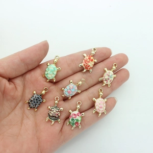 Hand holding eight colorful enamel turtle alloy pendants with diverse floral patterns