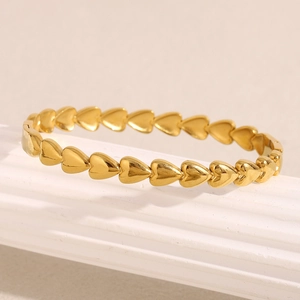 Close-up of polished 18K gold plated heart link bracelet on a white column stand