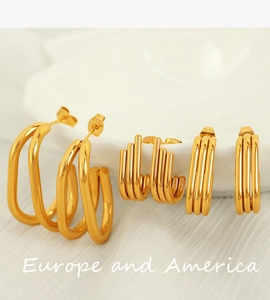 Detailed macro shot of layered U-shaped geometric gold earrings on white porcelain