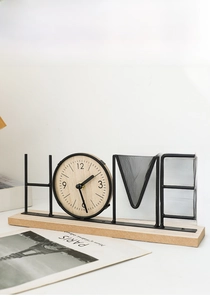 Detail of modern HOME metal clock with wooden dial on a solid wood base for desk decor