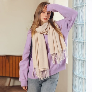 Écharpe beige en maille à chevrons avec glands portée sur un pull violet d'hiver