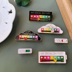 Close-up of enamel pins showing my social battery and mood tracker themes on metal
