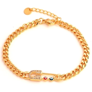 Detalle de pulsera de cadena cubana dorada con colgante de imperdible y motivos de ojo turco