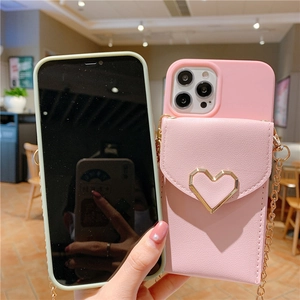 Pink crossbody phone case with heart wallet and metal chain strap shown in a cafe