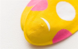 Macro shot of seamless toe stitching and vibrant yellow knit texture with pink dots