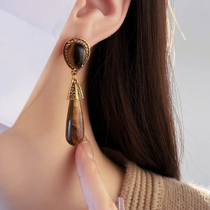 Close-up of vintage teardrop tiger eye earrings with gold plating and small diamonds