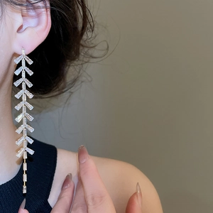 Détail des boucles d'oreilles longues à pampilles et cristaux portées par le mannequin