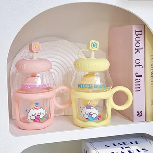 Pink and yellow glass straw cups with silicone handles in a decorative bookshelf setting