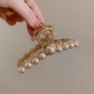 Dettaglio molletta per capelli dorata con doppie file di perle e manico a cuore con strass