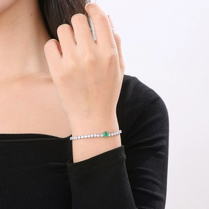 Detailed close-up of a heart-shaped green zircon tennis bracelet on a model wrist
