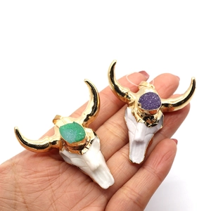 Bull skull resin pendants with natural green and purple crystals in a hand